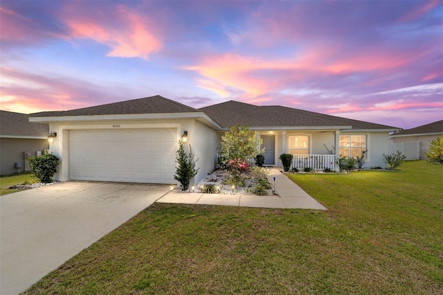 ranch-style home featuring a porch, concrete driveway, stucco siding, a lawn, and a garage