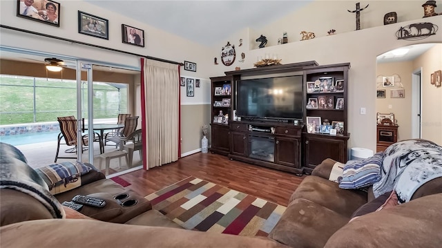 living room with arched walkways, vaulted ceiling, and dark wood finished floors