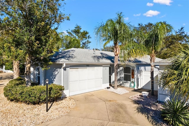 ranch-style home featuring roof with shingles, driveway, an attached garage, and stucco siding