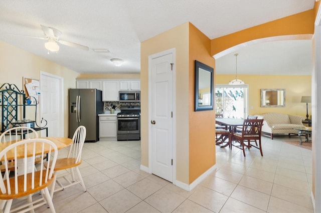 kitchen with light tile patterned floors, stainless steel appliances, pendant lighting, and white cabinets