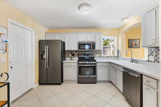 kitchen featuring a sink, white cabinets, light countertops, appliances with stainless steel finishes, and decorative backsplash