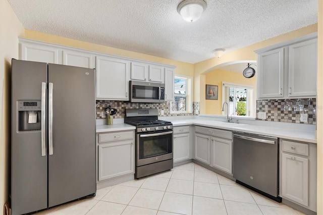 kitchen with light tile patterned floors, light countertops, appliances with stainless steel finishes, and a sink