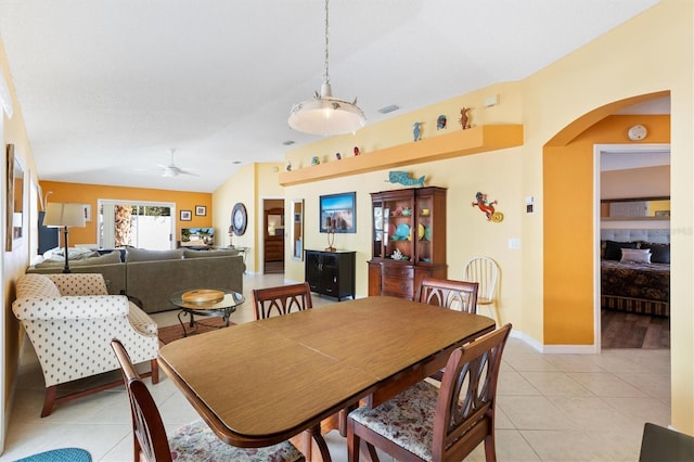 dining room featuring baseboards, arched walkways, a ceiling fan, lofted ceiling, and light tile patterned flooring