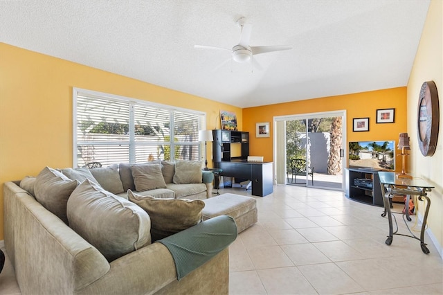 living area featuring a healthy amount of sunlight, ceiling fan, a textured ceiling, and light tile patterned floors