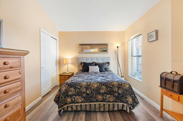 bedroom featuring light wood-type flooring, baseboards, and lofted ceiling