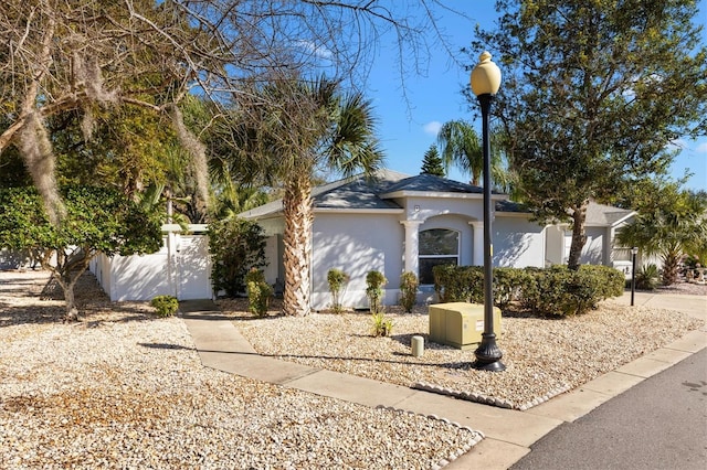 ranch-style house featuring an attached garage, fence, and stucco siding