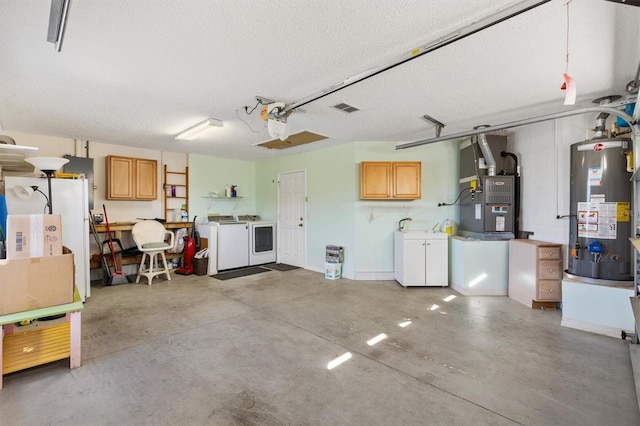 garage featuring water heater, visible vents, heating unit, and separate washer and dryer