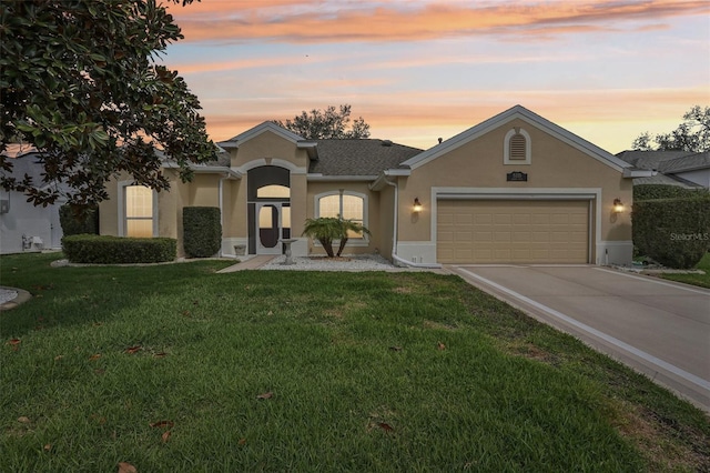 view of front of home with a front yard, concrete driveway, an attached garage, and stucco siding