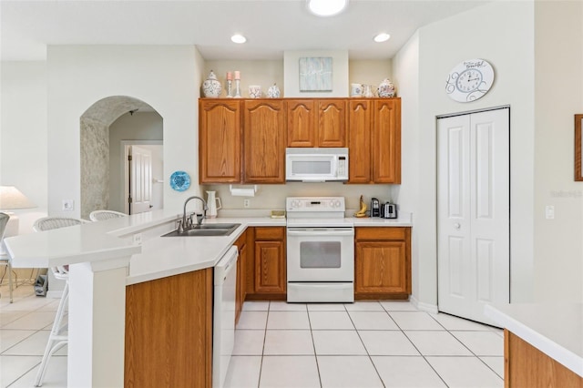 5135 Aurora Dr, Leesburg, FL 34748 - kitchen with a peninsula, white appliances, a sink, light countertops, and brown cabinetry