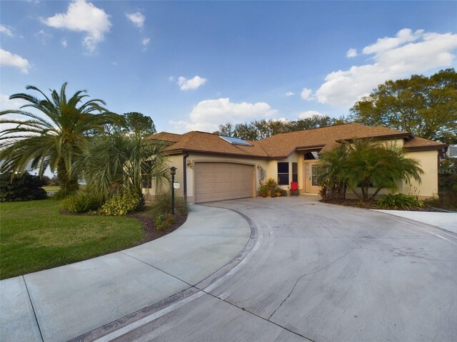 view of front of home with stucco siding, a front lawn, concrete driveway, and a garage