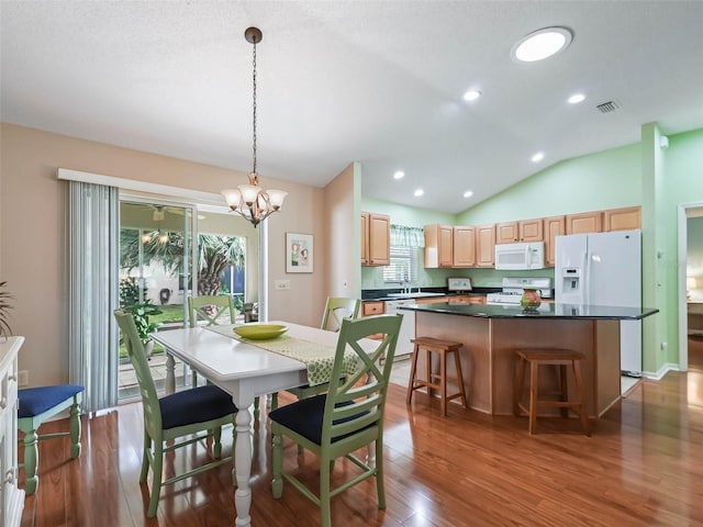 dining area featuring dark wood finished floors, visible vents, vaulted ceiling, and a wealth of natural light