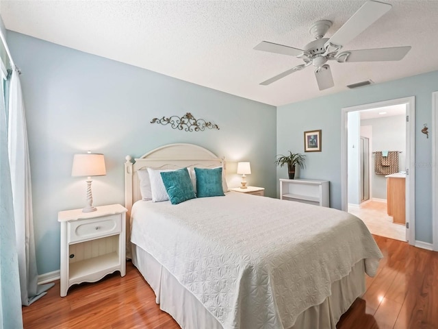 bedroom featuring visible vents, a ceiling fan, a textured ceiling, wood finished floors, and baseboards