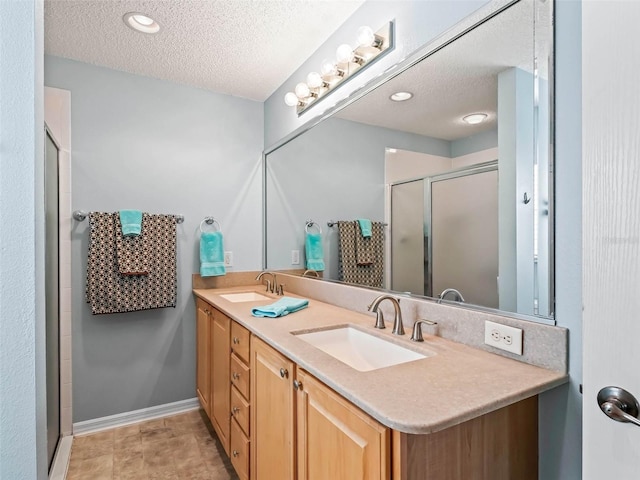 bathroom featuring double vanity, a shower stall, a textured ceiling, and a sink