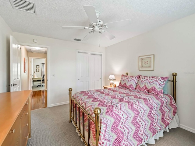 bedroom featuring light carpet, a textured ceiling, visible vents, and a closet