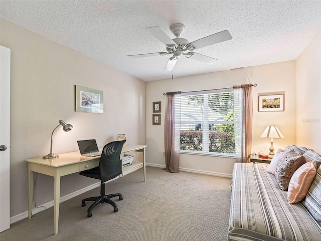 office space with light carpet, a textured ceiling, a ceiling fan, and baseboards