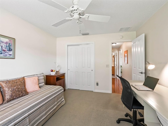 office area with light carpet, ceiling fan, visible vents, and a textured ceiling