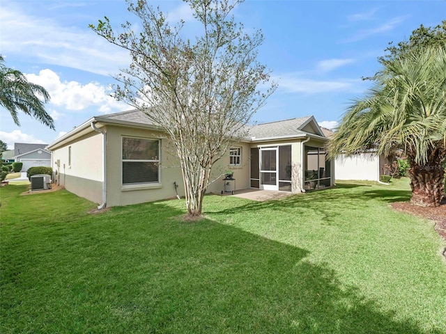 rear view of house with a shingled roof, central AC unit, a lawn, a sunroom, and stucco siding