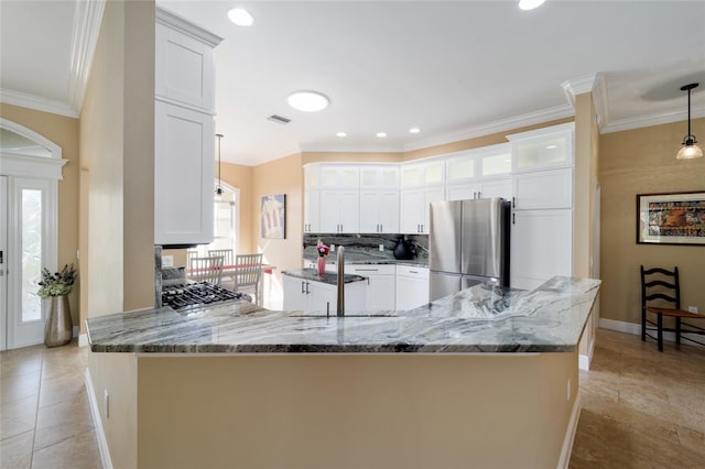 kitchen featuring a peninsula, baseboards, freestanding refrigerator, decorative backsplash, and stone countertops