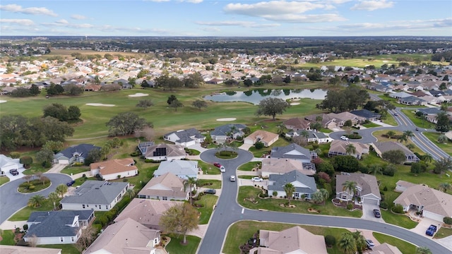 drone / aerial view featuring golf course view, a water view, and a residential view