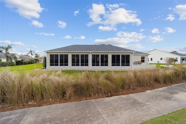 rear view of house featuring a sunroom and a shingled roof