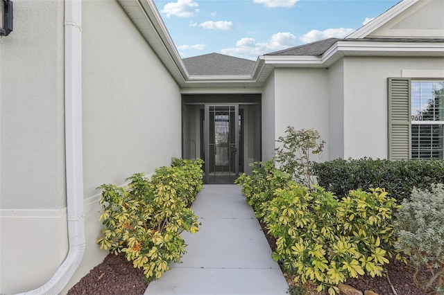 property entrance featuring a shingled roof and stucco siding