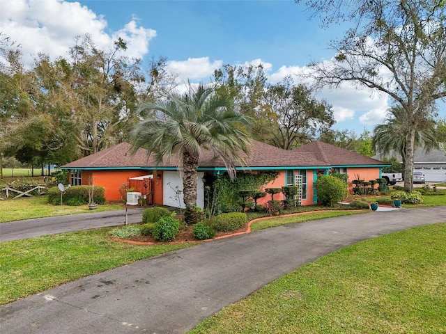 ranch-style house featuring a front lawn and ac unit