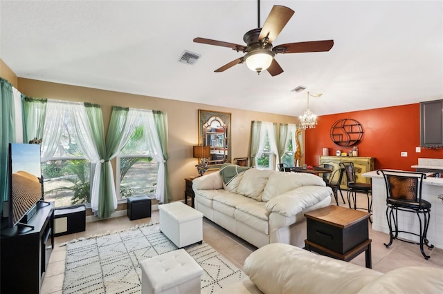 living room with ceiling fan with notable chandelier and light tile patterned floors