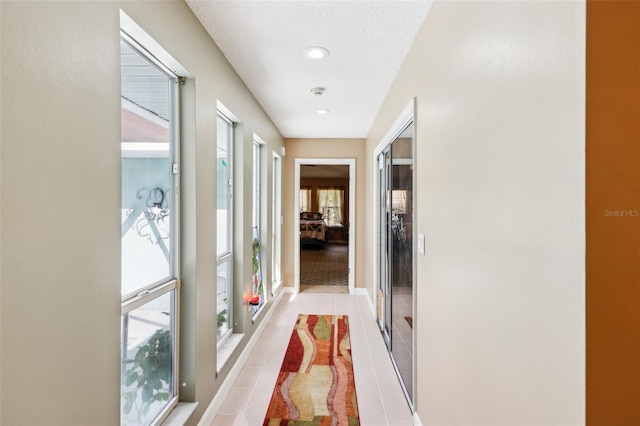 hall with light tile patterned floors and a textured ceiling