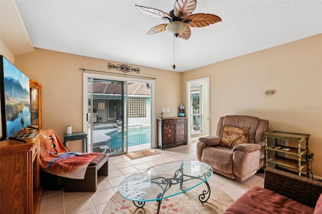 living room with light tile patterned floors, ceiling fan, and a textured ceiling