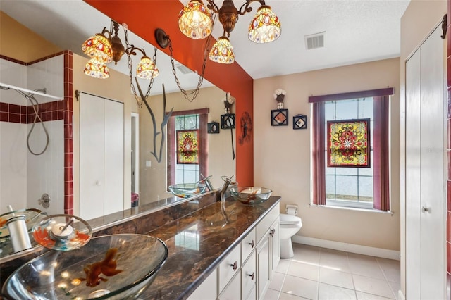 bathroom featuring vanity, tiled shower, toilet, and tile patterned floors