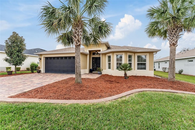 view of front facade featuring decorative driveway, an attached garage, a front yard, and stucco siding