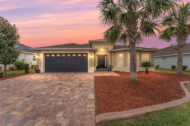 view of front facade with a garage, decorative driveway, and stucco siding