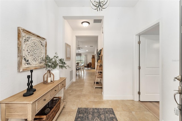 corridor featuring baseboards, visible vents, a chandelier, and light tile patterned flooring