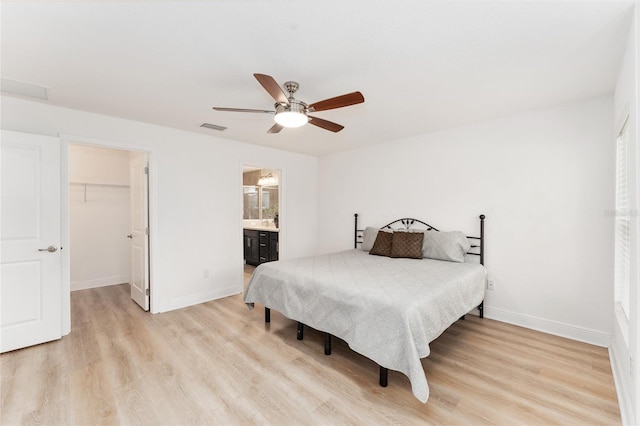 bedroom with light wood finished floors, baseboards, a spacious closet, and visible vents