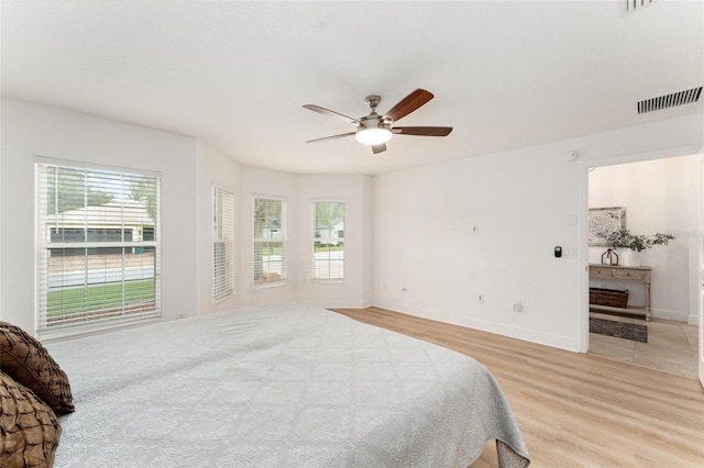 bedroom with light wood-style flooring, visible vents, ceiling fan, and baseboards