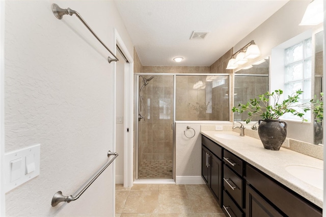 bathroom featuring double vanity, a stall shower, visible vents, and a sink