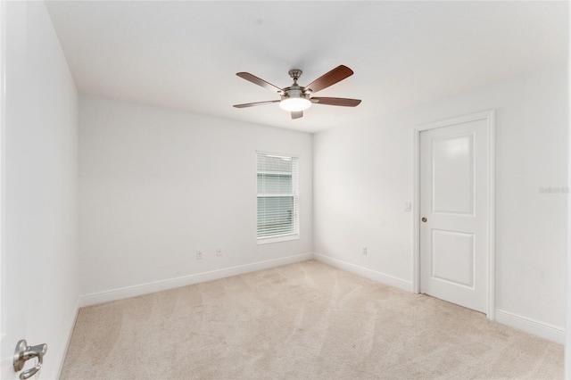 spare room featuring light carpet, ceiling fan, and baseboards