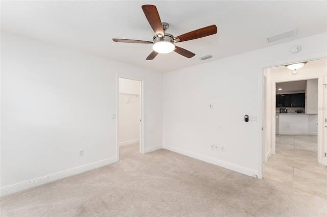 spare room featuring light carpet, ceiling fan, visible vents, and baseboards