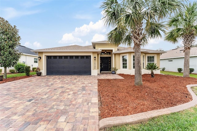 ranch-style home with a garage, decorative driveway, and stucco siding