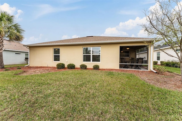 rear view of house with a lawn and stucco siding