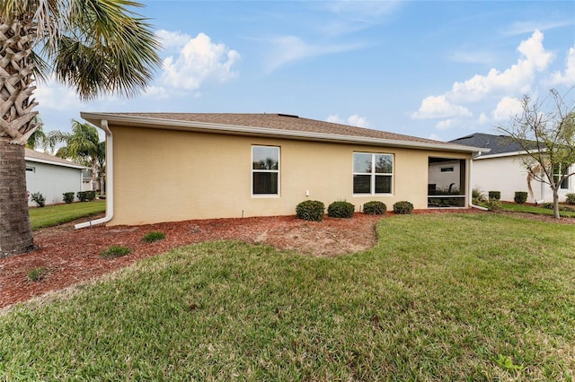 rear view of property with a lawn and stucco siding