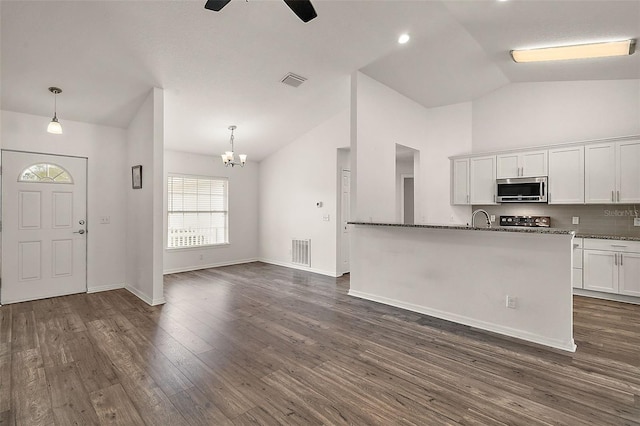 kitchen featuring white cabinetry, lofted ceiling, dark stone counters, dark wood-type flooring, and pendant lighting