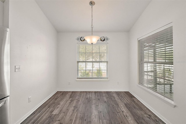 unfurnished dining area featuring vaulted ceiling and dark hardwood / wood-style flooring