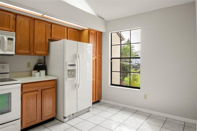 kitchen with light countertops, white appliances, brown cabinetry, and plenty of natural light