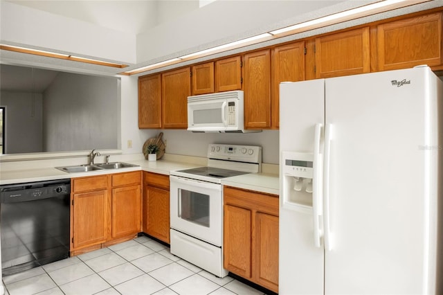 kitchen featuring white appliances, brown cabinets, light countertops, a sink, and light tile patterned flooring