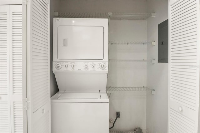 clothes washing area featuring laundry area, electric panel, and stacked washer and clothes dryer