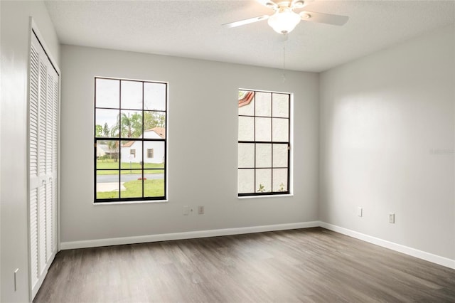 empty room featuring a ceiling fan, a textured ceiling, baseboards, and wood finished floors