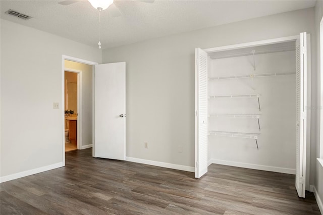 unfurnished bedroom featuring baseboards, visible vents, dark wood finished floors, and a closet