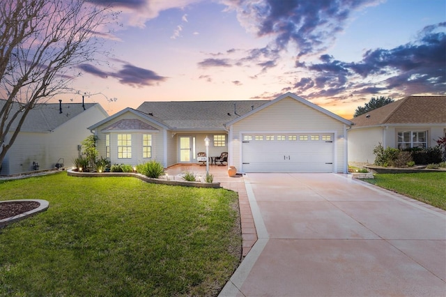 ranch-style home with concrete driveway, a lawn, and an attached garage