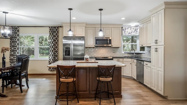 kitchen featuring a center island, pendant lighting, appliances with stainless steel finishes, a sink, and a kitchen breakfast bar